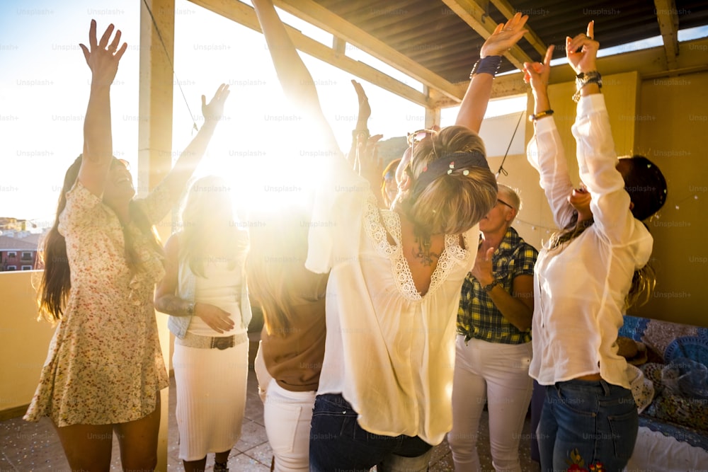 Grupo activo feliz de jóvenes caucásicos libres mujer celebra y baila todos juntos con amistad - puesta de sol a la luz de fondo para el concepto de fiesta en casa - Felicidad para el grupo