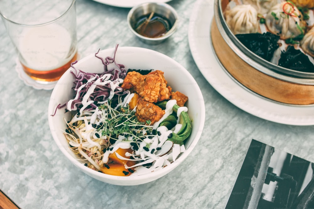 Pan-Asian food - different dim sums in bamboo bowl and salad. Lunch for two with beer