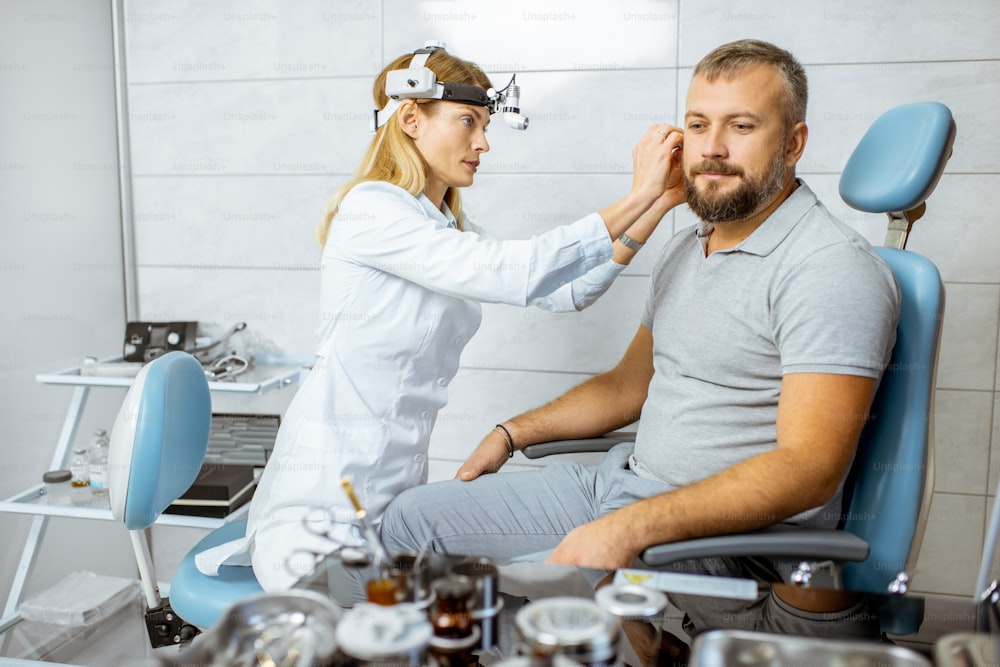 Female otolaryngologist with adult patient during a medical examination of an ear at the procedure room of the ENT office