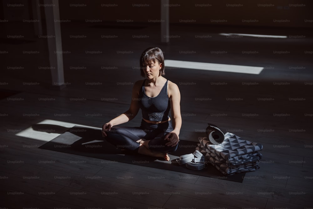 Young calm yogi woman in lotus yoga pose. Yoga studio interior.