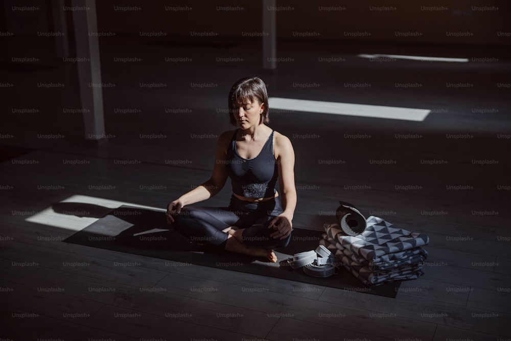 Joven mujer yogui tranquila en pose de yoga de loto. Interior del estudio de yoga.