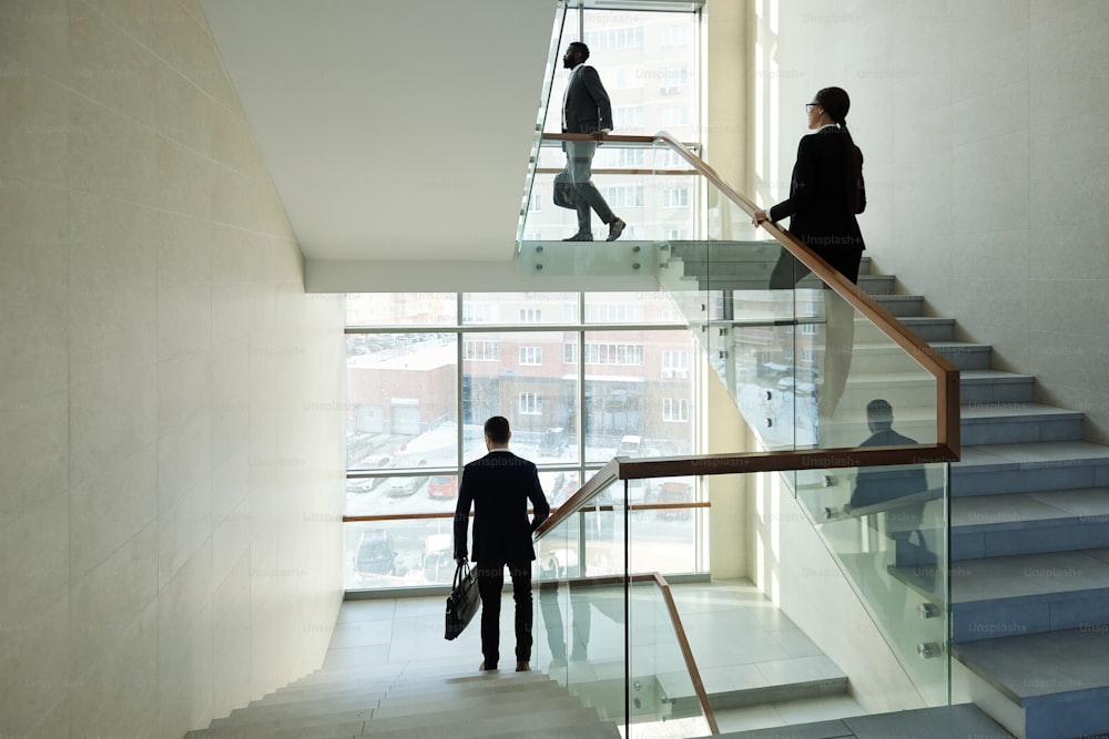 Young business people walking upstairs for work and elegant office manager moving downstairs while going home