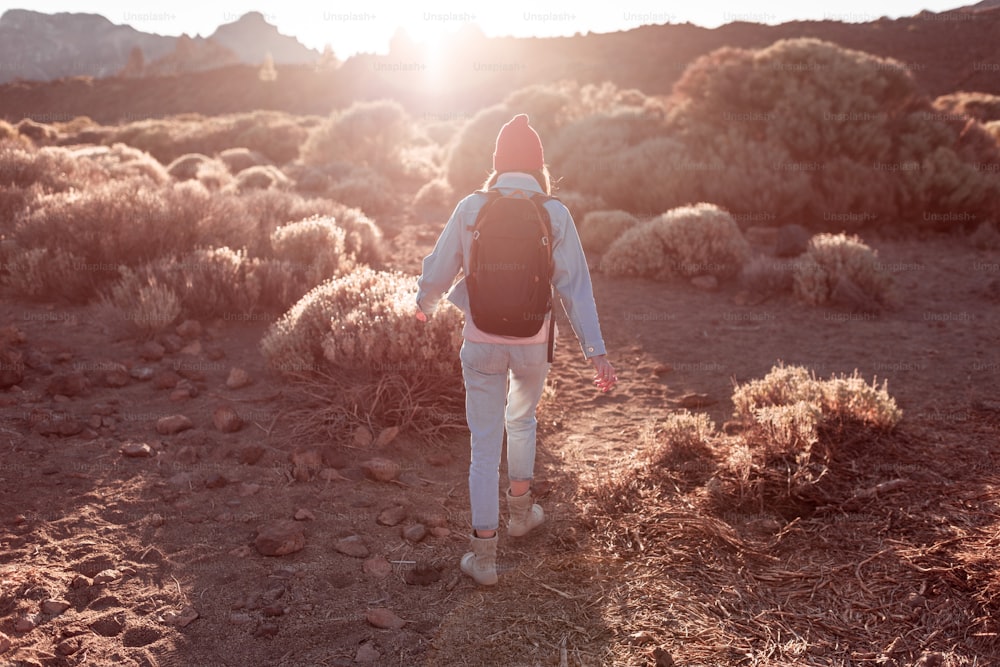 Landscape view on a beautiful volcanic valley with woman hiking on a sunset. Traveling on Teide national park on Tenerife island, Spain