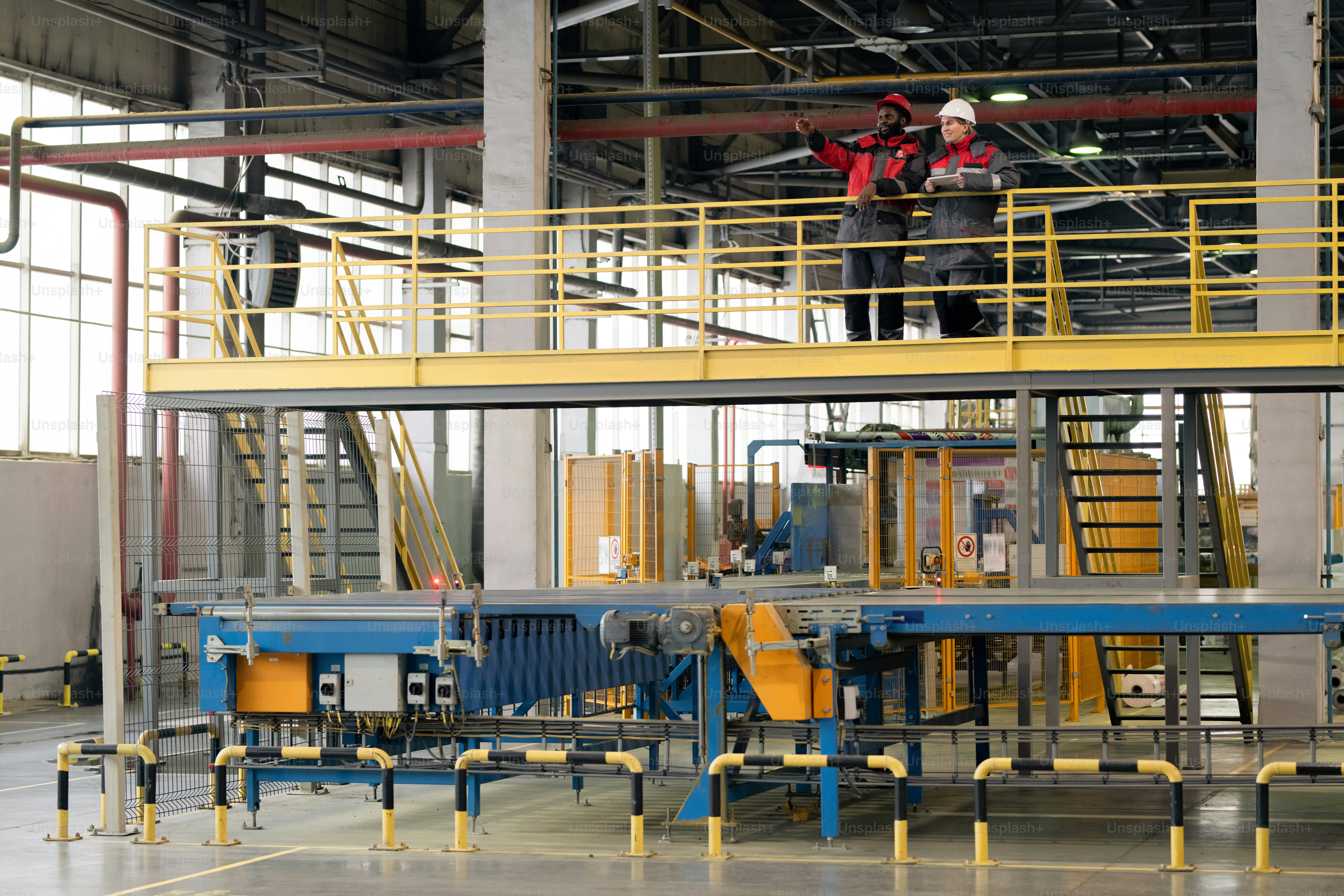 Des collègues multiethniques en combinaison de protection debout sur le pont et contrôlant les processus de l’usine