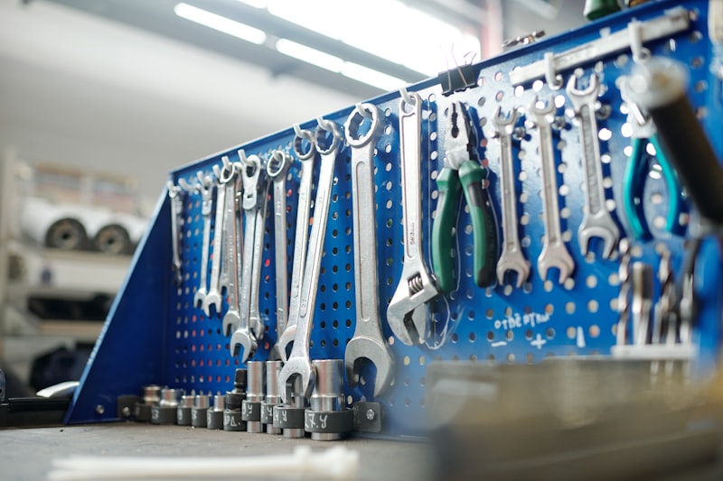 Kit of wrenches and other handtools for technical work hanging on hooks in row inside workshop of industrial plant