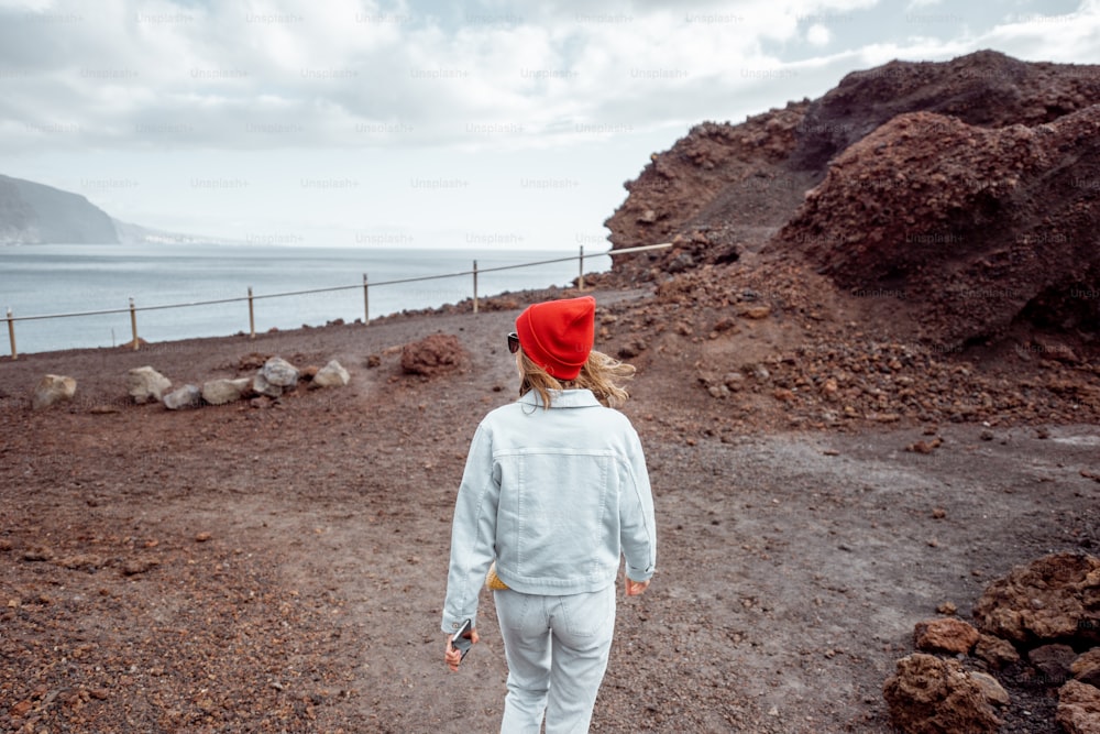 Mulher elegante despreocupada desfrutando de uma viagem em paisagens rochosas, caminhando no caminho vulcânico do deserto na ilha de Tenerife
