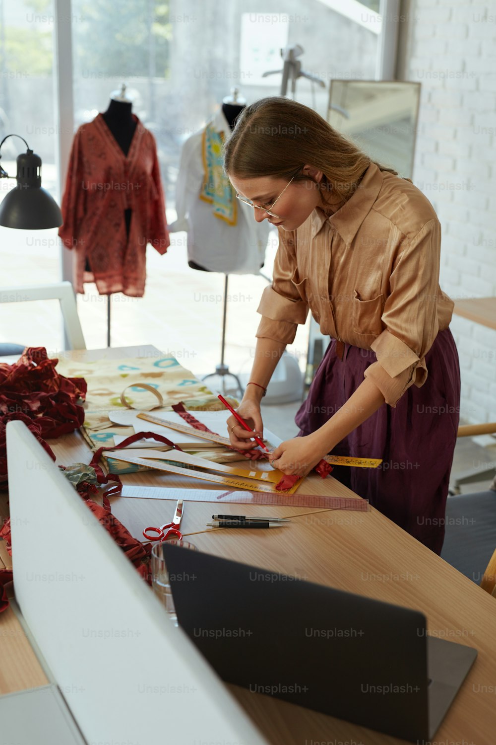Lavoro. Stilista di moda presso Atelier. Donna lavoratrice autonoma di successo che crea abiti eleganti in officina. Bellissimo tessuto di misurazione su misura per abito elegante. Lavoro di creatività per l'avvio di un'impresa.