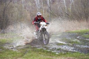 Piloto de Motorcross correndo em pista de lama durante competição ao ar livre