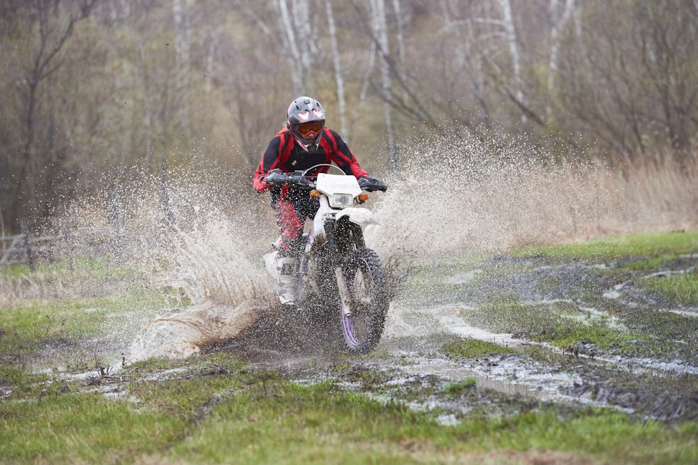 Pilota di motocross in pista di fango durante la competizione all'aperto