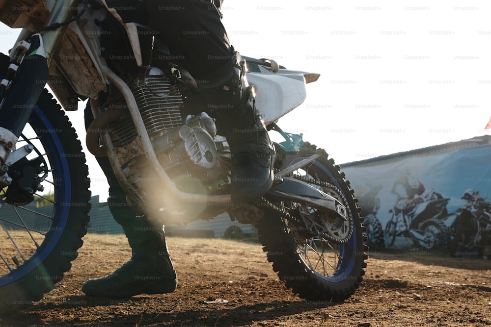 Pedal de cambio de motociclista irreconocible mientras se prepara para conducir moto al aire libre, efecto de luz solar