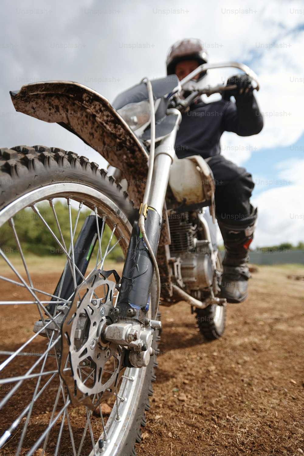 Focus on dirty motorbike wheel on off-road track, motorcyclist ready for race