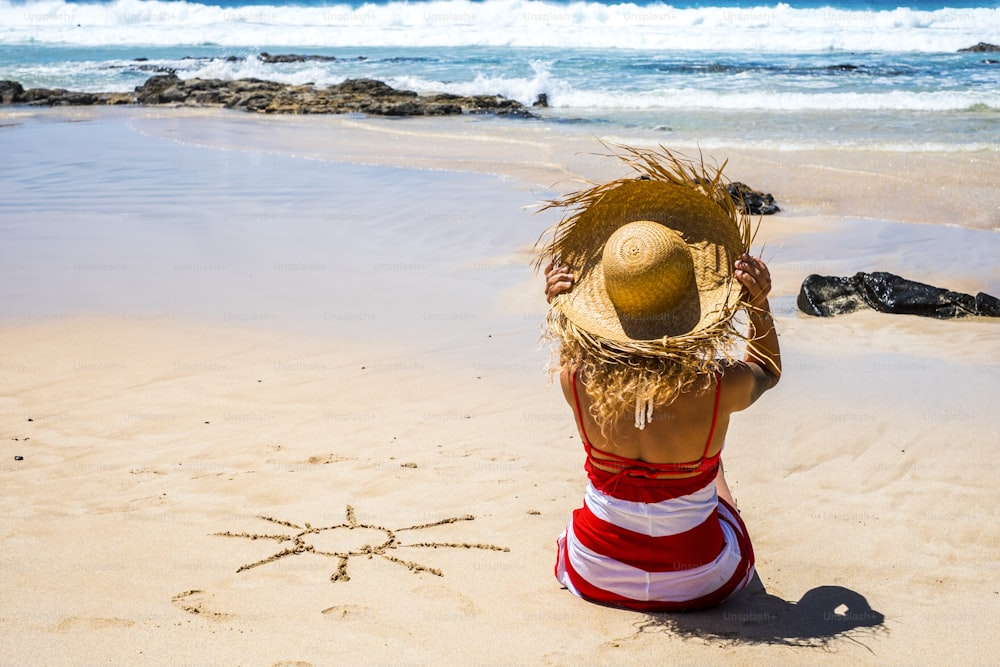 Mujer turista y turismo lifestlye en vacaciones de verano vacaciones en la playa en un día soleado y sol diseñado en la arena - océano de agua azul en el fondo y concepto de relax