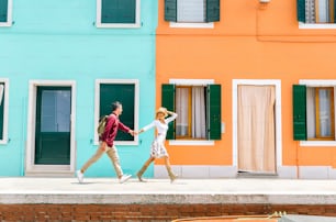 Paar im Urlaub in Venedig, Italien. Mann und verliebte Frau spazieren in der Stadt Burano vor bunten Gebäuden.
