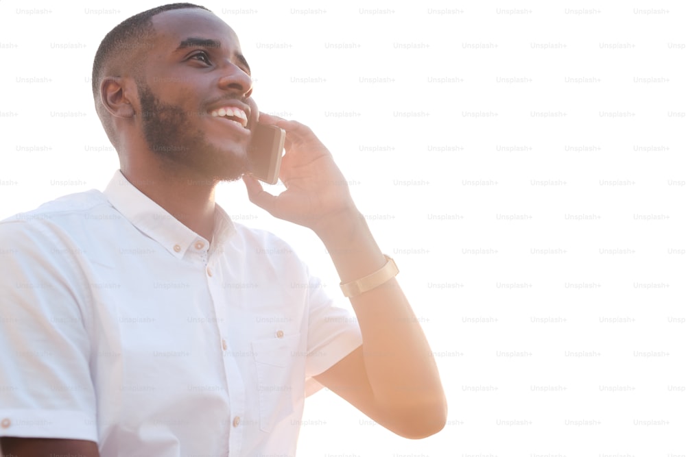 Young successful African broker or agent in white shirt holding smartphone by ear while calling clients and consulting them in front of camera
