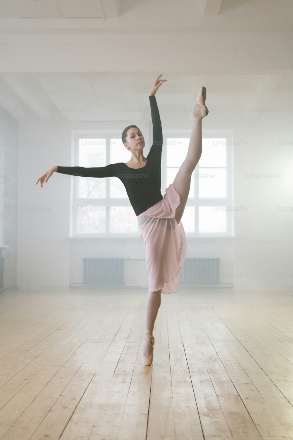 Portrait of beautiful ballet dancer stretching her leg during ballet dance in dance studio
