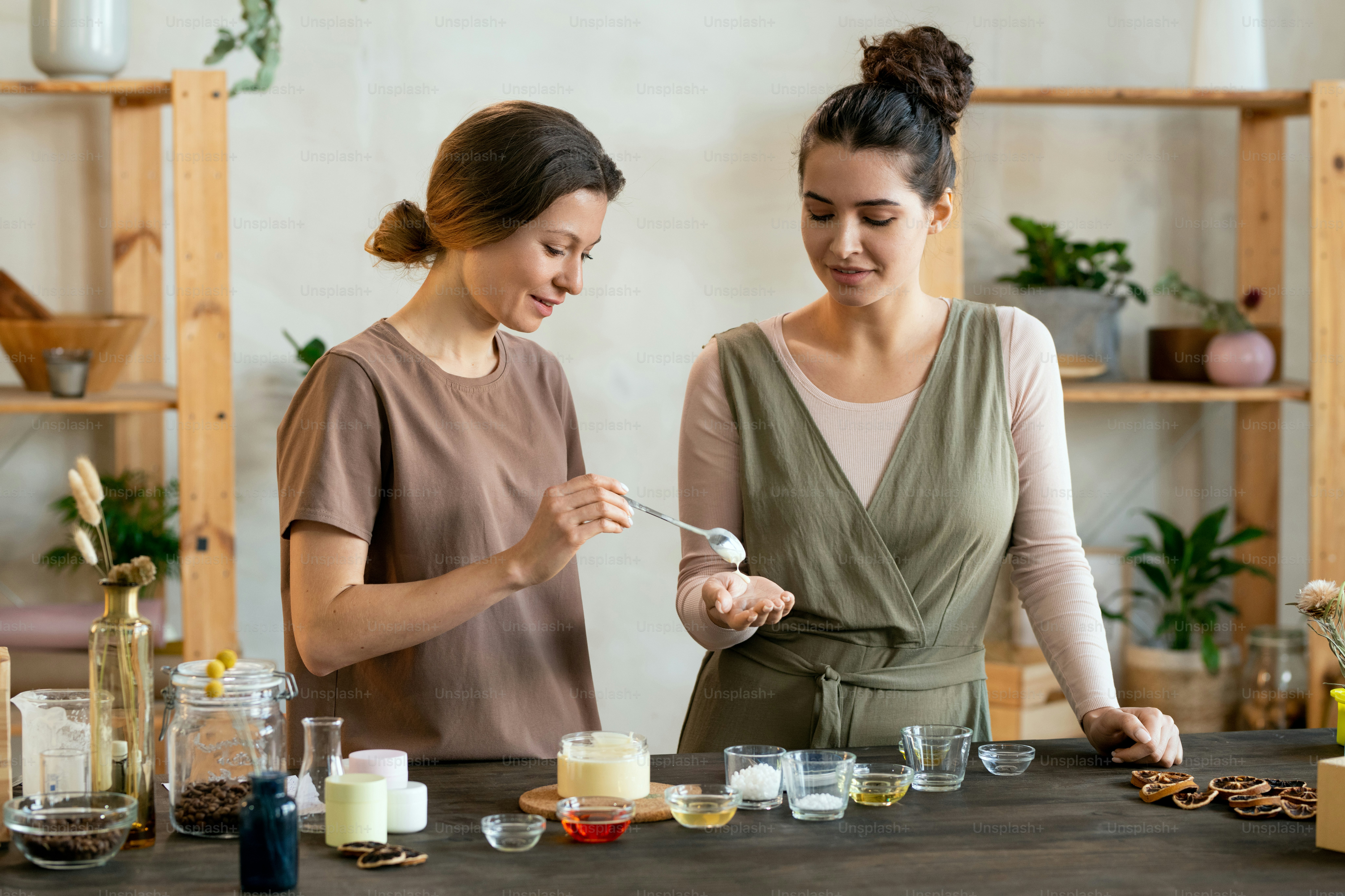 自然な手作りの化粧品を作るのを手伝う彼女の友人の手のひらに新鮮な手作りの液体石鹸の塊を置く若い女性