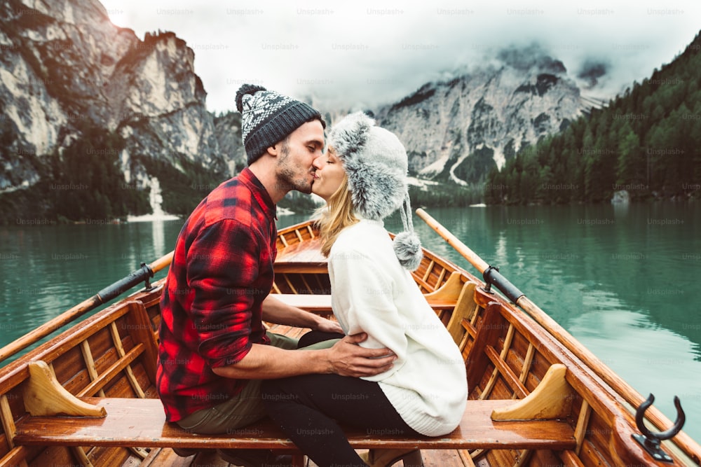 Romantic kiss of a couple of adults visiting an alpine lake at Braies Italy. Tourist in love spending loving moments together at autumn mountains. Couple, wanderlust and travel concept.