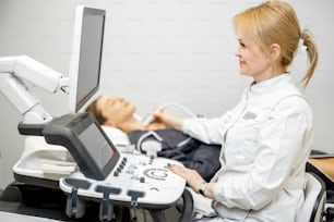 Médico examinando la tiroides de una paciente femenina con ecografía en una clínica médica. Concepto de salud y bienestar.