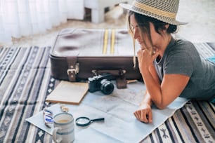 Caucasian woman planning vacation travel with map and guide at home, female people plan next holidays vacation while relaxing on the floor - pretty girl wanderlust concept