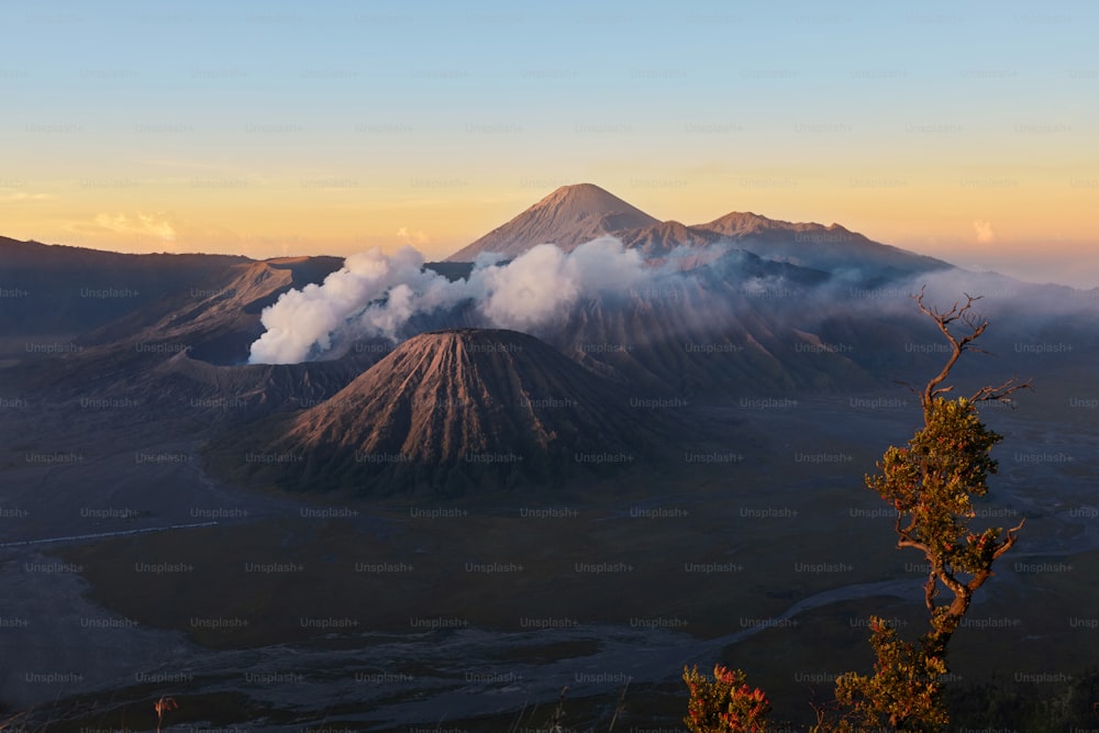 クレーターの深さを持つ煙の雲の中の活火山。インドネシアの東ジャワにあるグヌンブロモ火山の後ろの日の出。