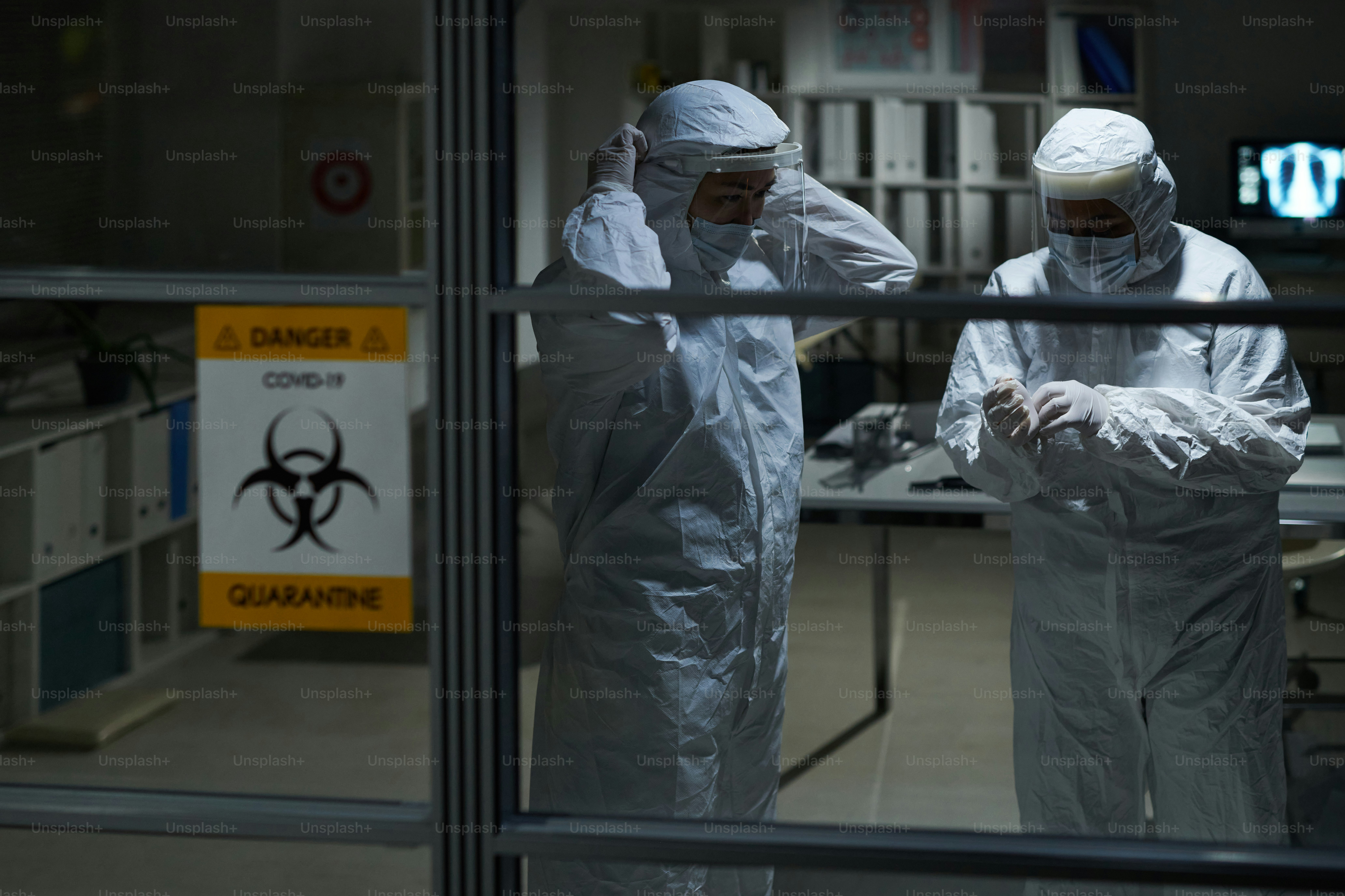 Two young female clinicians in protective workwear getting ready for