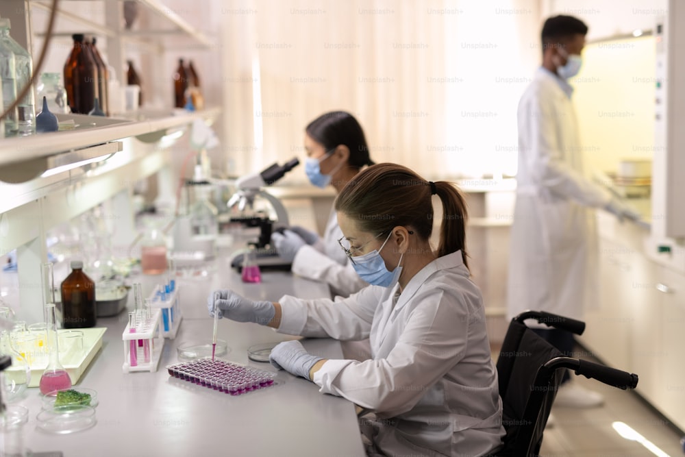 Grupo de científicos contemporáneos con batas blancas trabajando en laboratorio