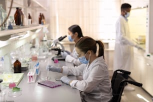 Group of contemporary scientists in whitecoats working in lab