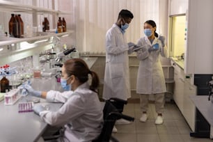 Chimici interculturali in camice da laboratorio che lavorano insieme con nuove sostanze liquide