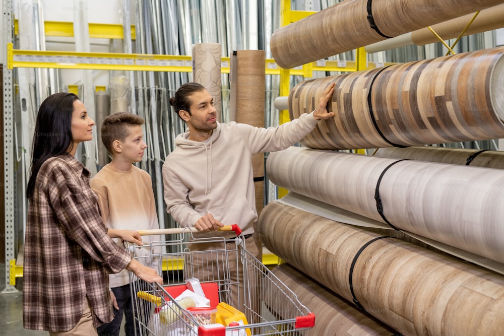 Family of father, mother and son choosing new linoleum in hardware store