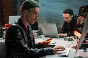 Krimineller mit Plastikkarte schaut auf Computerbildschirm im Büro
