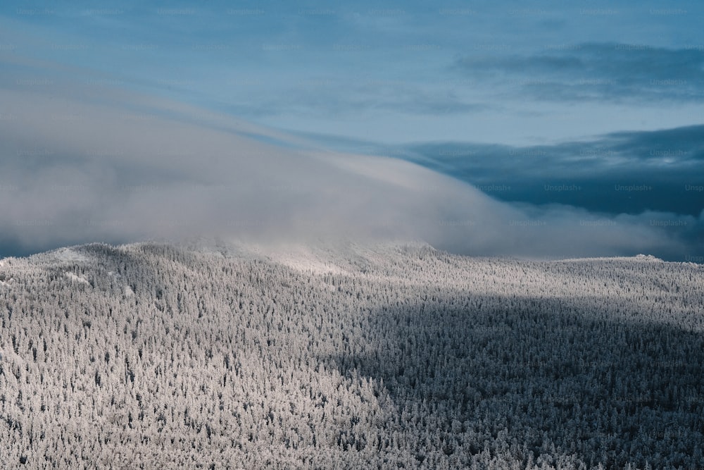 Paisaje invernal de la cadena montañosa de Taganay cubierta de nieve y nubes contra el cielo azul