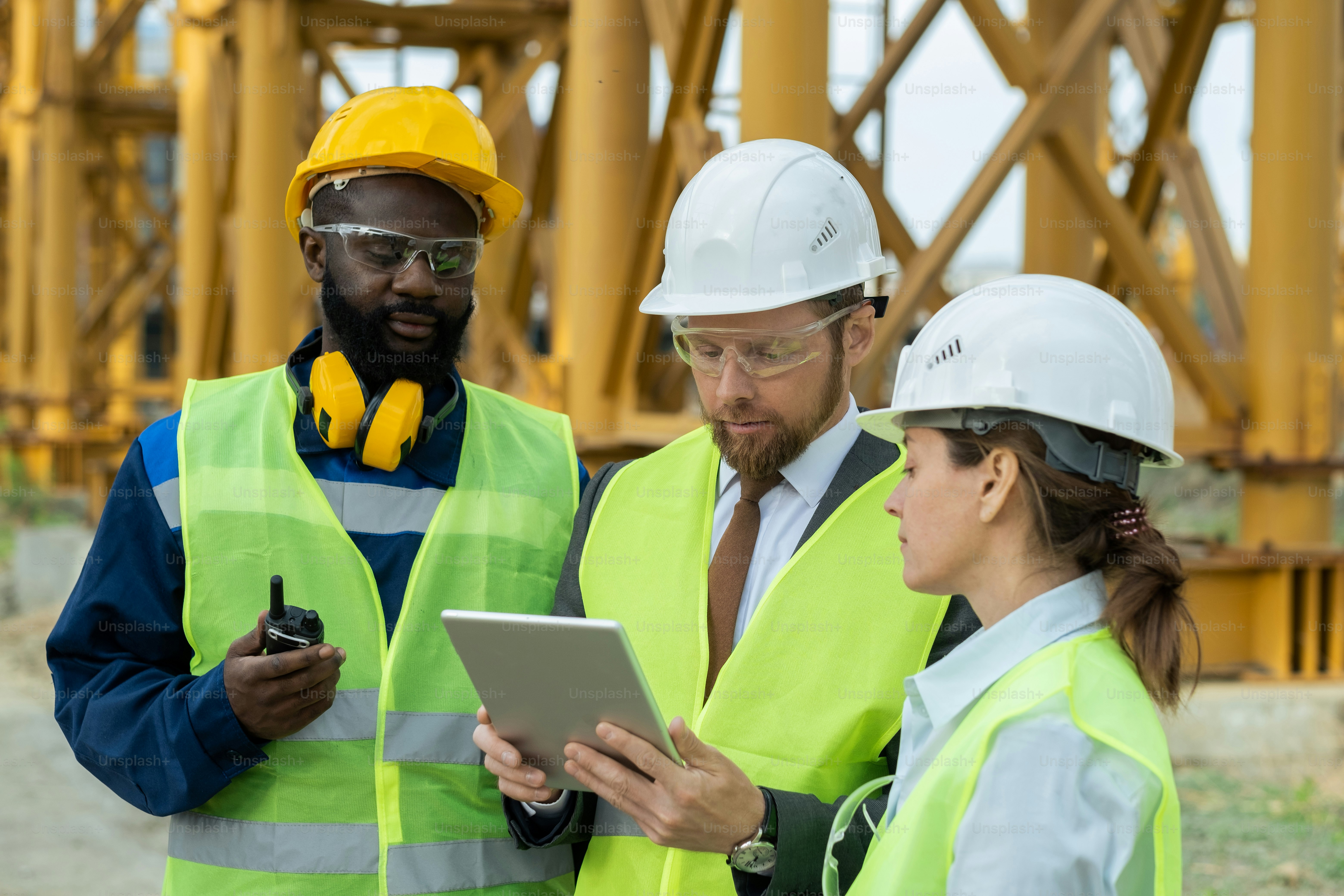 Group of young intercultural builders looking at tablet display
