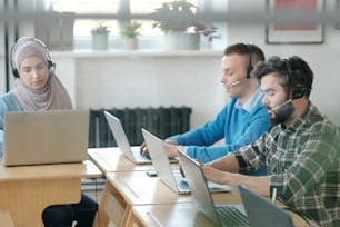 Group of young operators consulting clients online while working in office