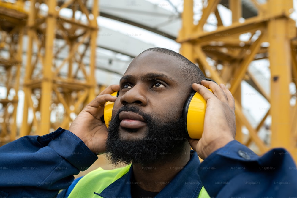Close-up of construction worker in protective headphones working on construction site