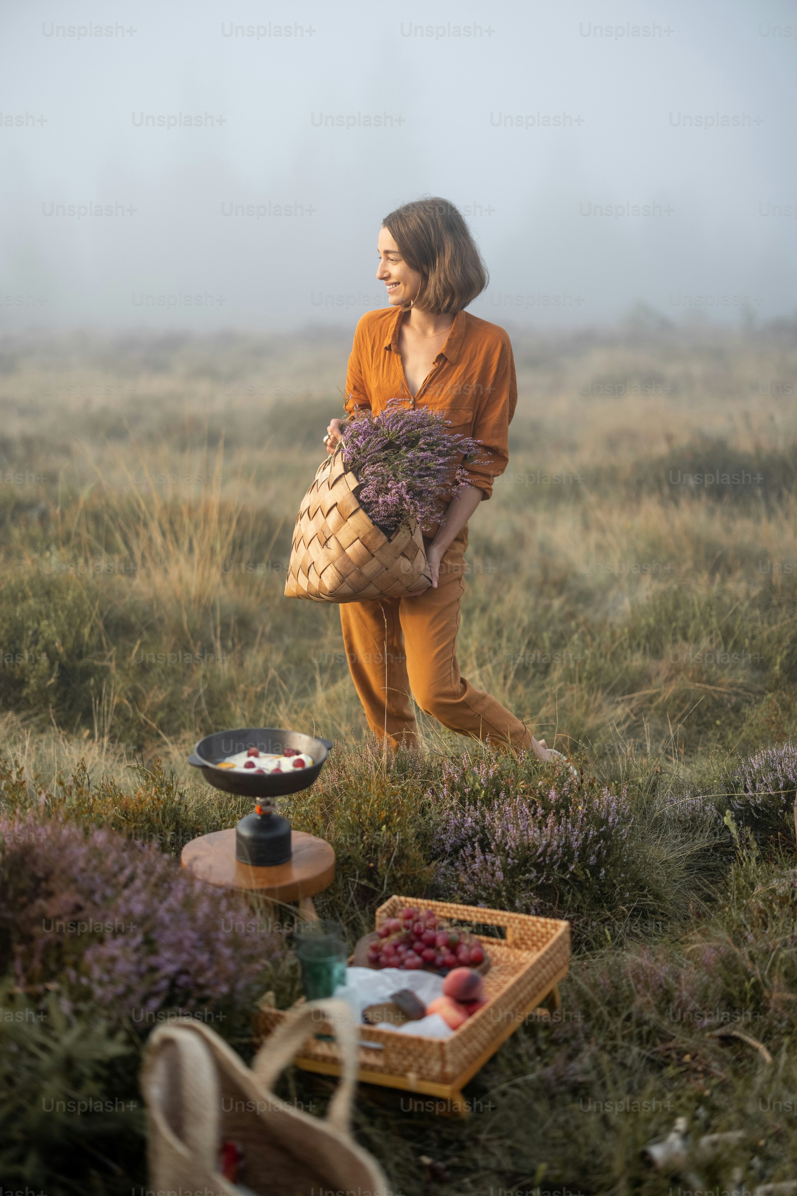 山で朝食のピクニックをしている、拾いたてのヘザーブーケを持つかわいい女性のポートレート