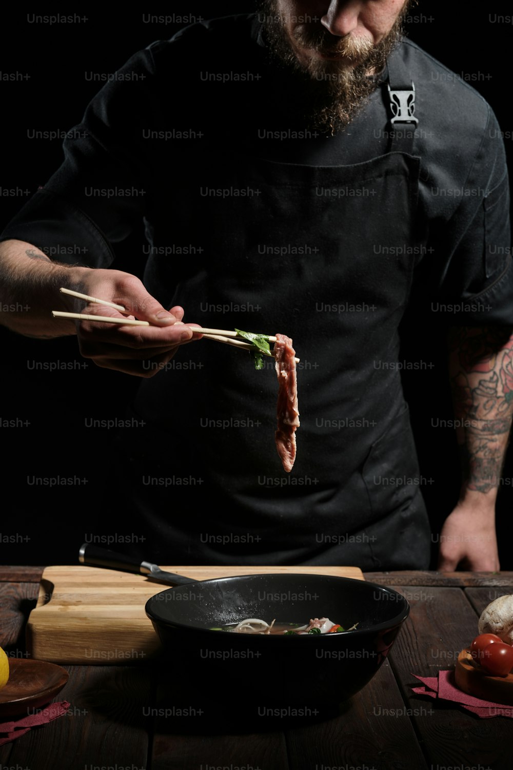 Close up of chef's hands tasting beef noodle bowl with chopsticks
