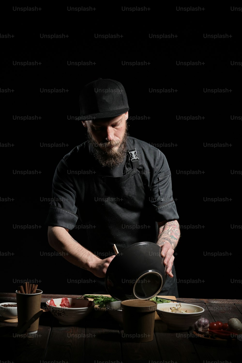 Ritratto in studio di chef brutale che prepara cibo asiatico, usando bacchette, piatti, cibo fresco