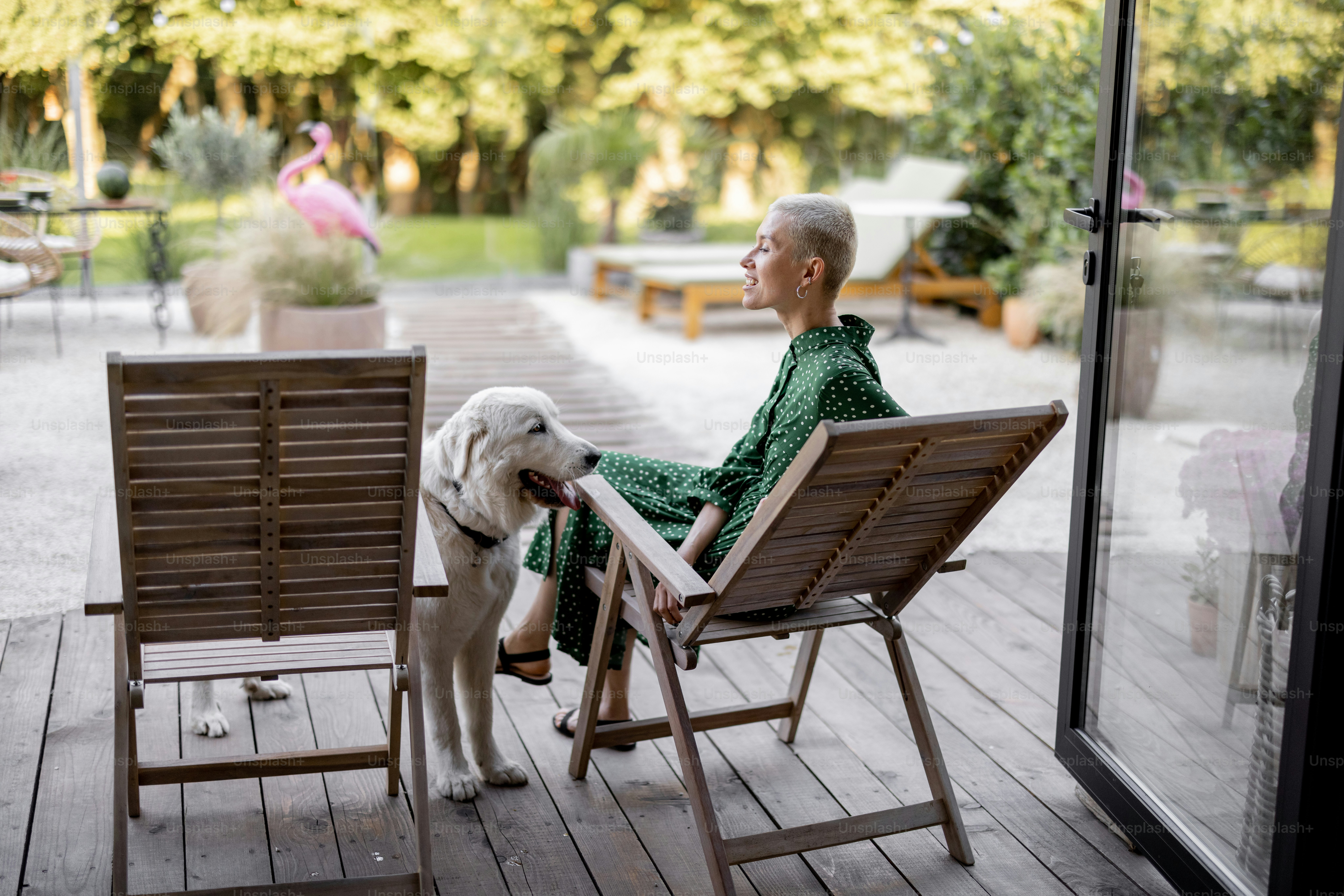 A woman in a green dress beside a large white dog on a patio