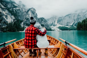 Romantic couple on a boat visiting an alpine lake at Braies Italy. Tourist in love spending loving moments together at autumn mountains. Concept about travel, couple and wanderust.