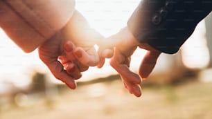 Immagine ravvicinata di due amanti che si tengono per mano al tramonto - Concetto di fiducia, amore, relazione e supporto