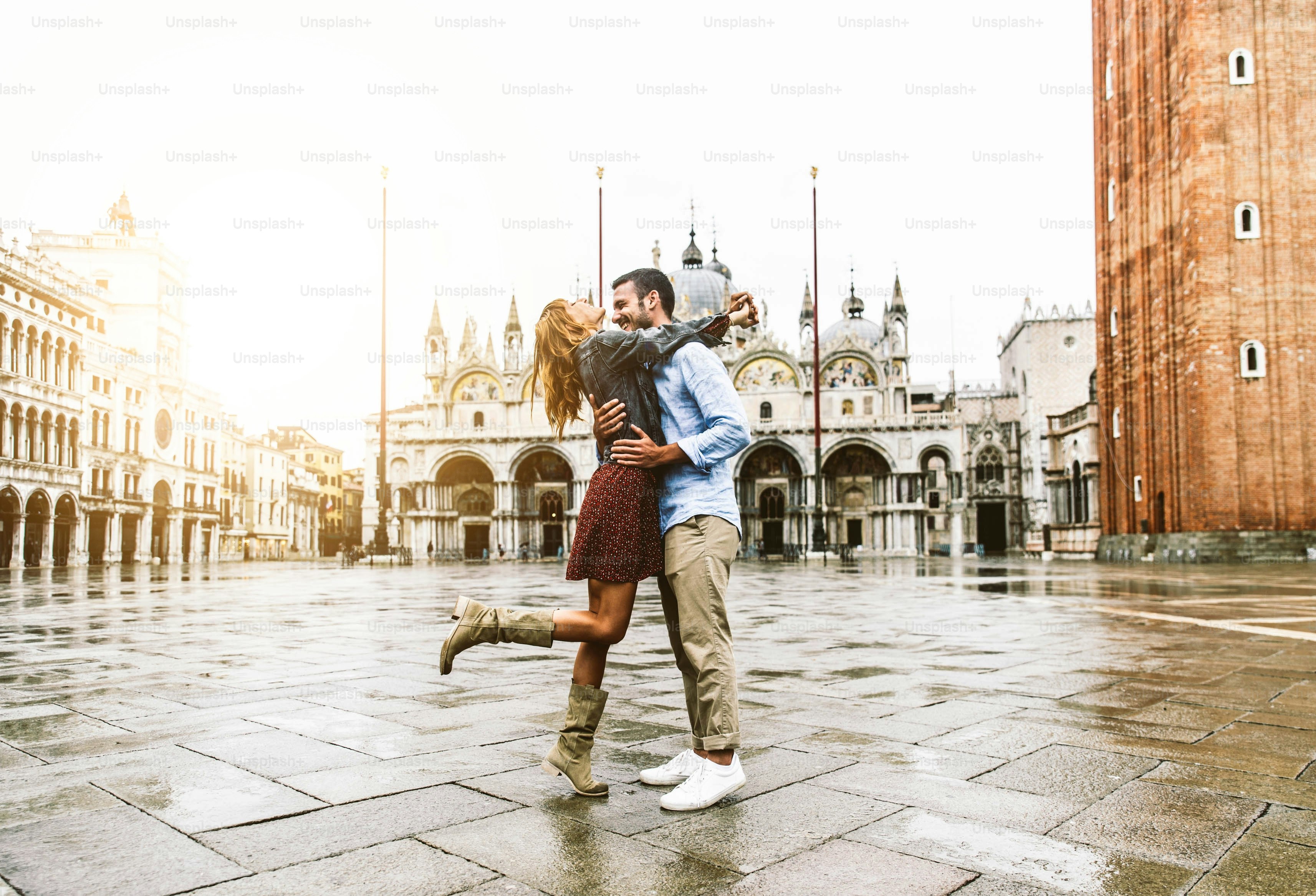Couple of tourists on vacation in Venice, Italy - Two lovers having fun on city street at sunset - Tourism and love concept