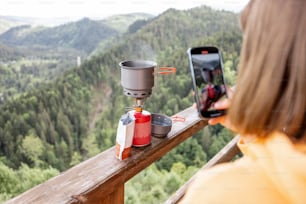 여행자는 하이킹 과정을 위한 음식을 준비하는 사진, 산 배경에 가스 버너로 끓는 물 사진을 찍습니다.