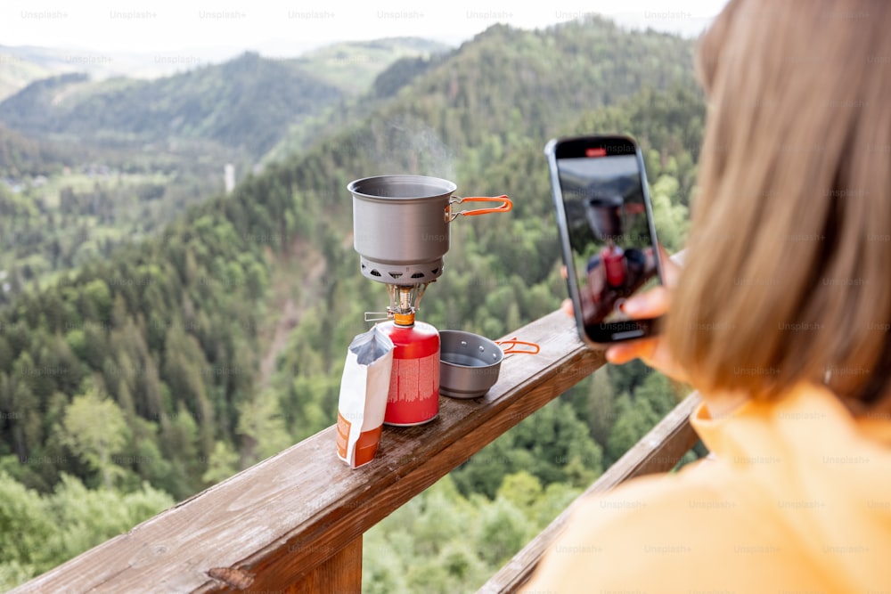 Traveler takes a picture of preparing food for hiking process, boiling water with a gas burner on mountains background