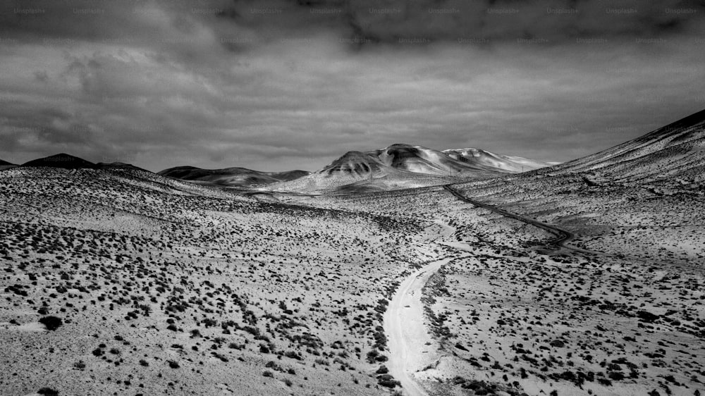 Schwarz-Weiß-dramatische Landschaft mit Auswirkungen des Klimawandels auf die globale Erwärmung und Wüstenbildung. Weißer Straßenweg mitten in den Bergen mit Mobody.