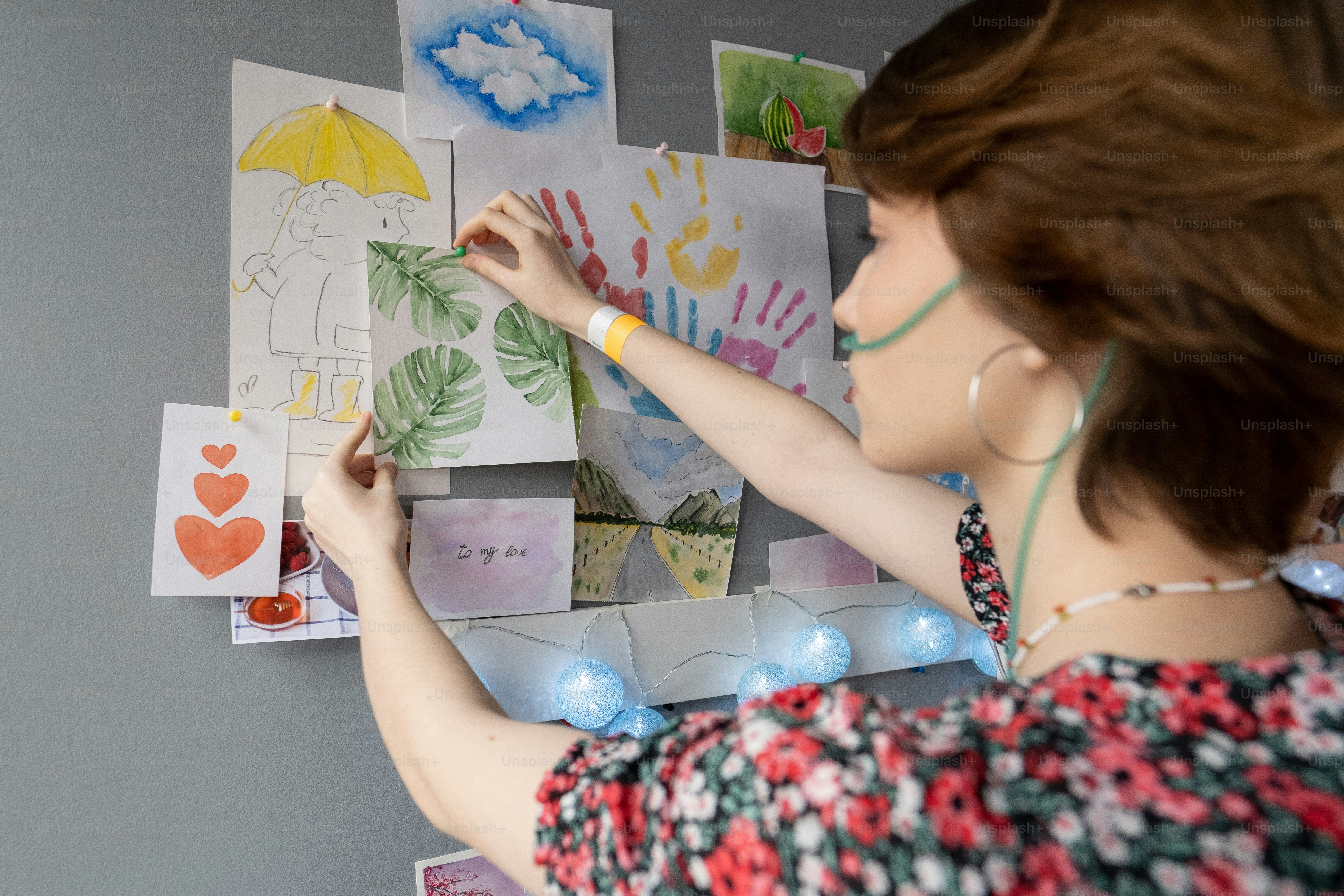 病棟の壁に友人の絵を描いている酸素鼻管を持つ若い病気の女性患者