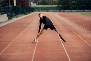 A sportsman with artificial leg warming up at stadium on running track.