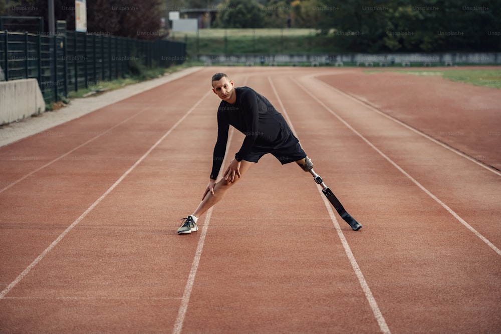 A sportsman with artificial leg warming up at stadium on running track.