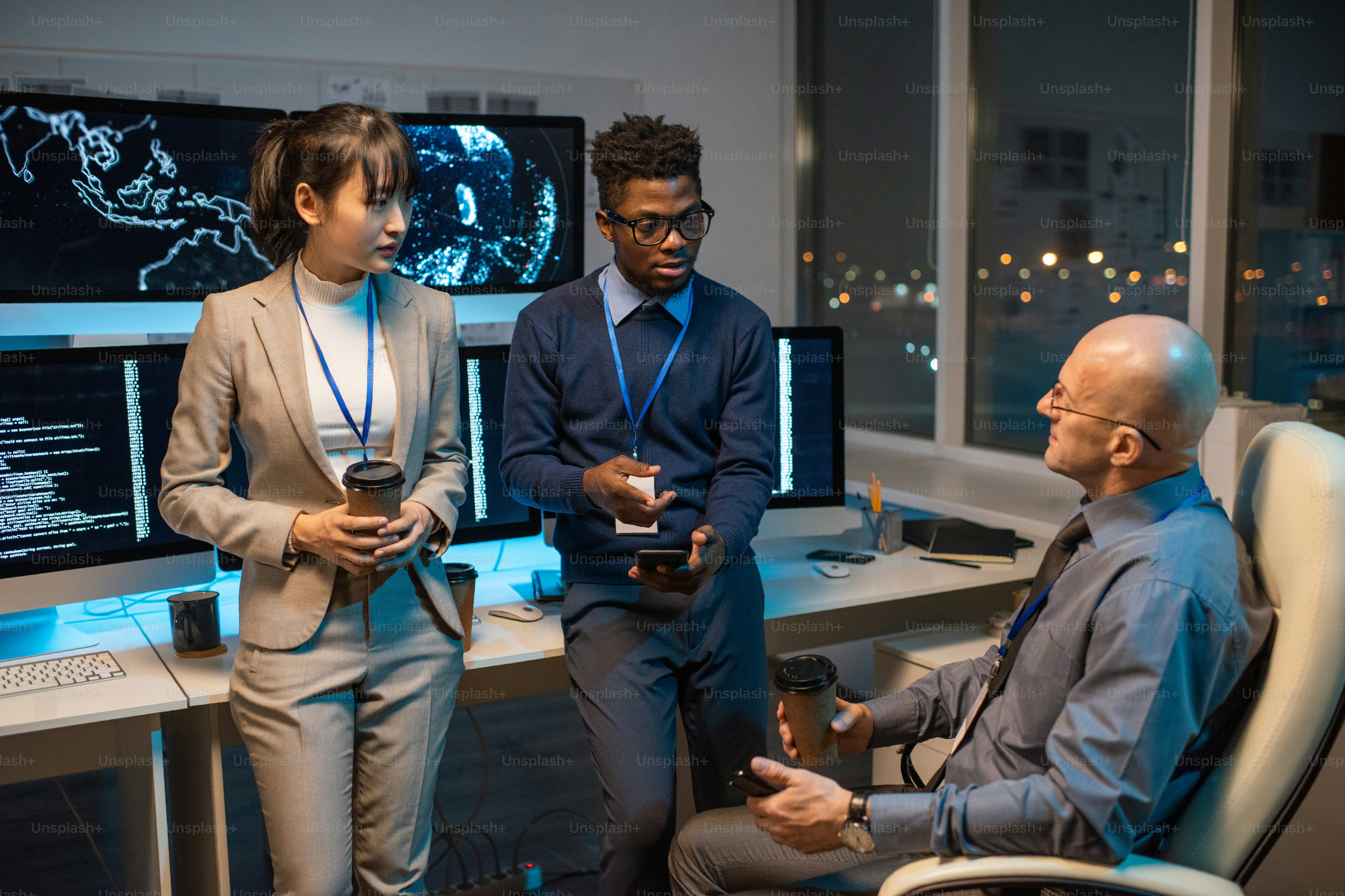 Two businessmen with smartphones and drinks discussing working points while young Asian female colleague listening to them