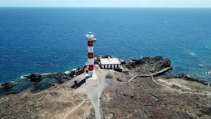 bella veduta aerea del faro vecchio e nuovo sulla scogliera di Tenerife di fronte all'oceano Atlantico. motociclista da solo guarda il mare