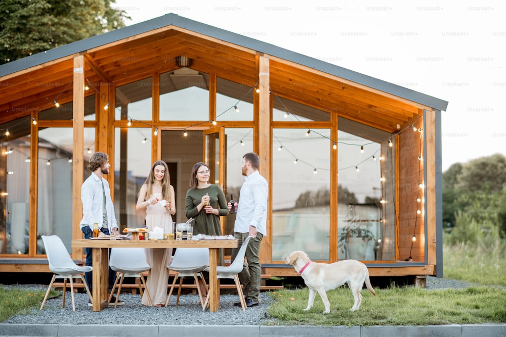 Four friends enjoying evening time together drinking beer on the backyard of the modern country house